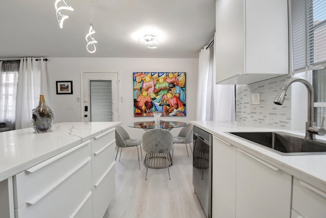 373 Piedmont H, Delray Beach, FL 33484 - kitchen with tasteful backsplash, light wood-style flooring, stainless steel dishwasher, a sink, and white cabinets