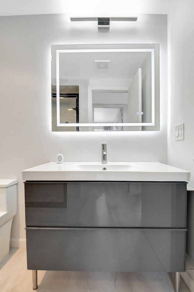 373 Piedmont H, Delray Beach, FL 33484 - bathroom featuring visible vents, toilet, vanity, and wood finished floors