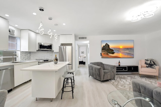 373 Piedmont H, Delray Beach, FL 33484 - kitchen featuring visible vents, appliances with stainless steel finishes, a sink, open floor plan, and a kitchen breakfast bar