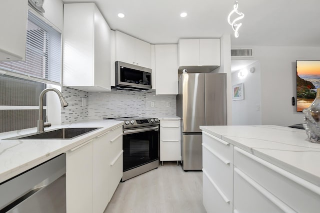 373 Piedmont H, Delray Beach, FL 33484 - kitchen featuring stainless steel appliances, backsplash, a sink, visible vents, and white cabinets