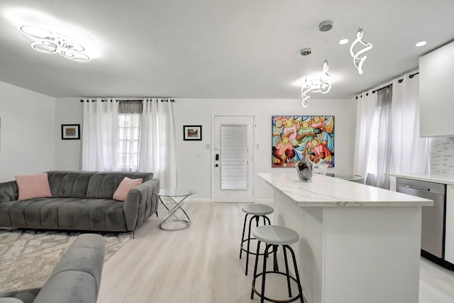 373 Piedmont H, Delray Beach, FL 33484 - kitchen with a kitchen island, a kitchen breakfast bar, dishwasher, decorative light fixtures, and light wood-style floors
