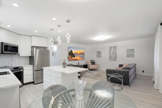 373 Piedmont H, Delray Beach, FL 33484 - kitchen with backsplash, a kitchen island, open floor plan, stainless steel appliances, and white cabinets