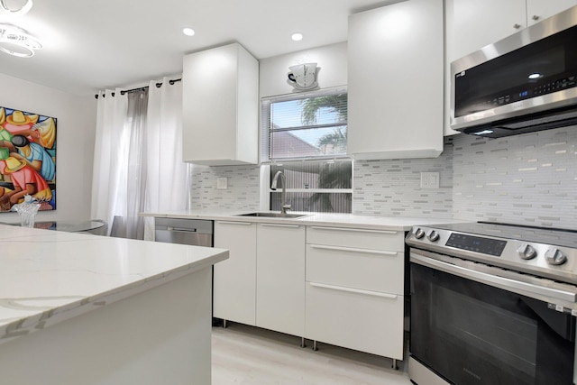 373 Piedmont H, Delray Beach, FL 33484 - kitchen featuring light stone counters, backsplash, a sink, stainless steel appliances, and white cabinets