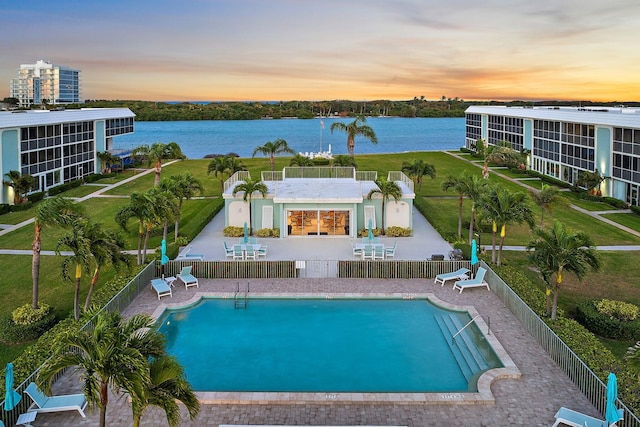 community pool with a patio, a fenced backyard, and a water view