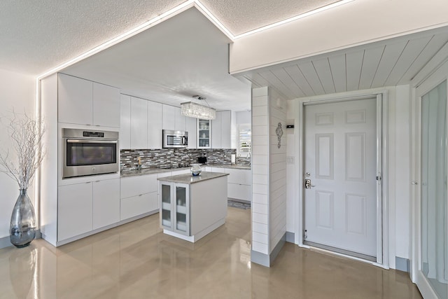 kitchen featuring modern cabinets, decorative backsplash, glass insert cabinets, white cabinets, and appliances with stainless steel finishes