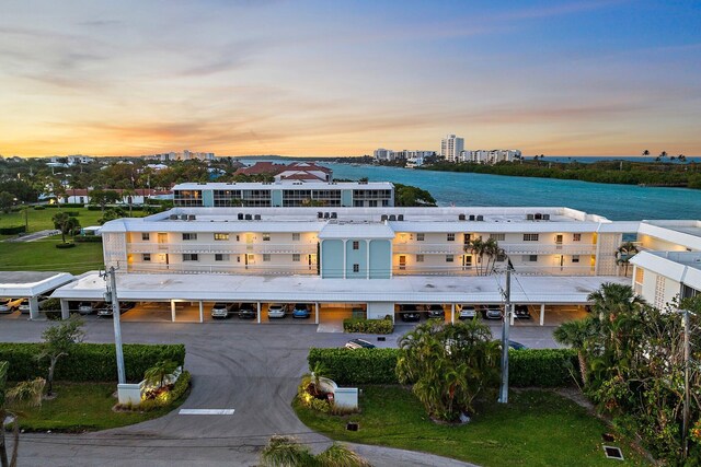 back of house featuring a parking lot and a water view