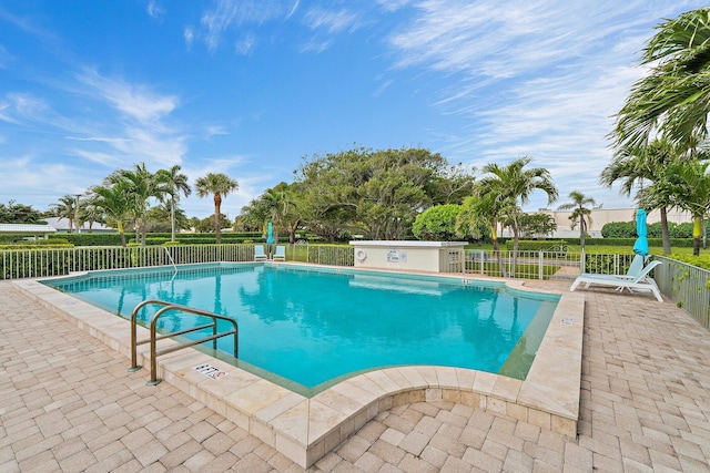 community pool with a patio and fence