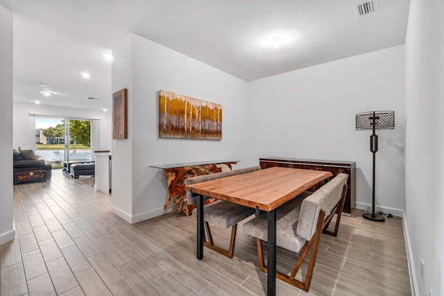 7113 Peters Ln, Delray Beach, FL 33446 - dining area with baseboards, visible vents, a textured ceiling, and wood finish floors