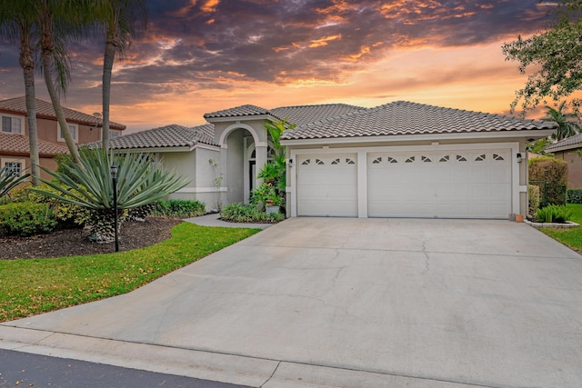 mediterranean / spanish-style house featuring a tiled roof, driveway, a garage, and stucco siding