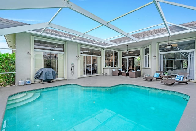 outdoor pool with an outdoor hangout area, a patio area, a ceiling fan, and glass enclosure