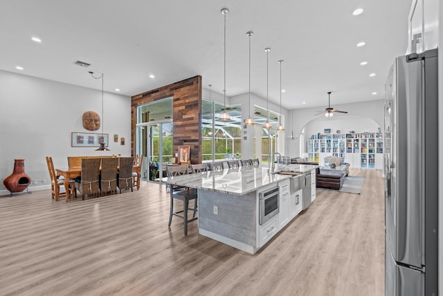 kitchen featuring a breakfast bar, open floor plan, light wood-style flooring, white cabinetry, and freestanding refrigerator