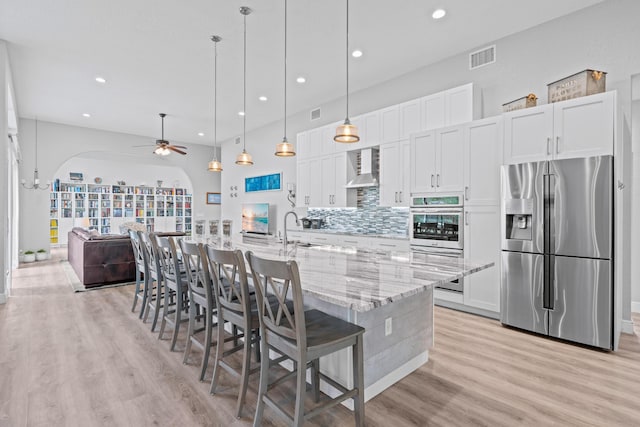 kitchen featuring a ceiling fan, wall chimney exhaust hood, recessed lighting, and stainless steel appliances