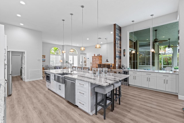 kitchen featuring a sink, light wood-type flooring, dishwasher, and white cabinetry