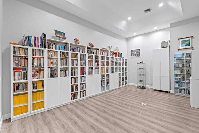 interior space with a tray ceiling, visible vents, recessed lighting, wood finished floors, and baseboards