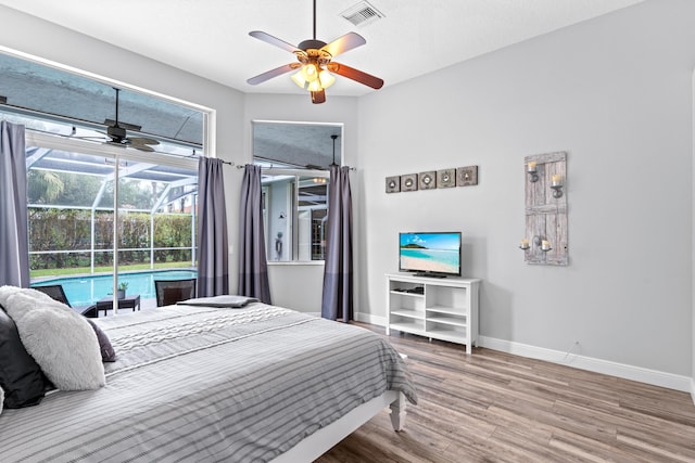 bedroom with baseboards, a ceiling fan, visible vents, a sunroom, and wood finished floors