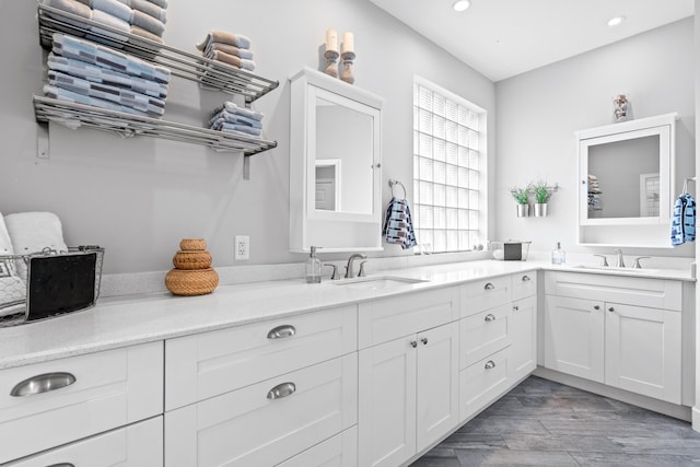 bathroom with wood finished floors, double vanity, a sink, and recessed lighting