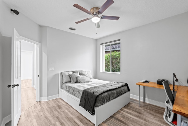 bedroom featuring visible vents, baseboards, a ceiling fan, and wood finished floors