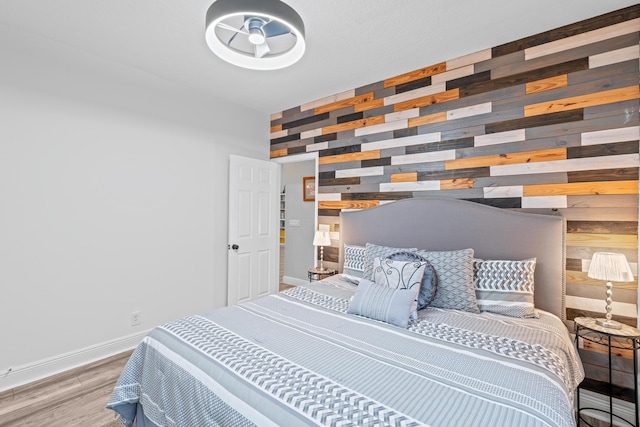 bedroom with wooden walls, baseboards, and wood finished floors