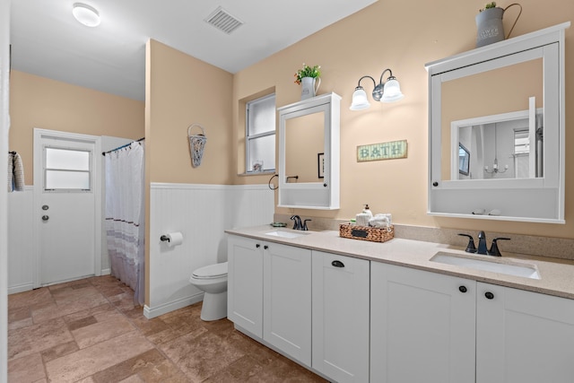 full bath featuring a wainscoted wall, visible vents, a sink, and toilet