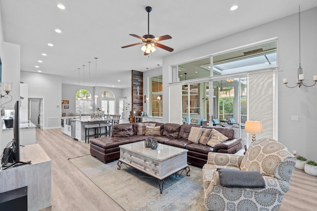 living room with recessed lighting, light wood-style flooring, and ceiling fan with notable chandelier