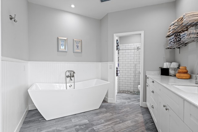 full bathroom featuring a stall shower, wood finished floors, vanity, and a wainscoted wall