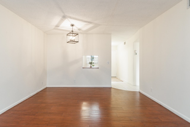 230 NE 26th Ave Unit 1030, Boynton Beach, FL 33435 - spare room featuring a textured ceiling, visible vents, baseboards, wood finished floors, and an inviting chandelier