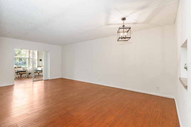230 NE 26th Ave Unit 1030, Boynton Beach, FL 33435 - spare room featuring a notable chandelier, a textured ceiling, baseboards, and wood finished floors