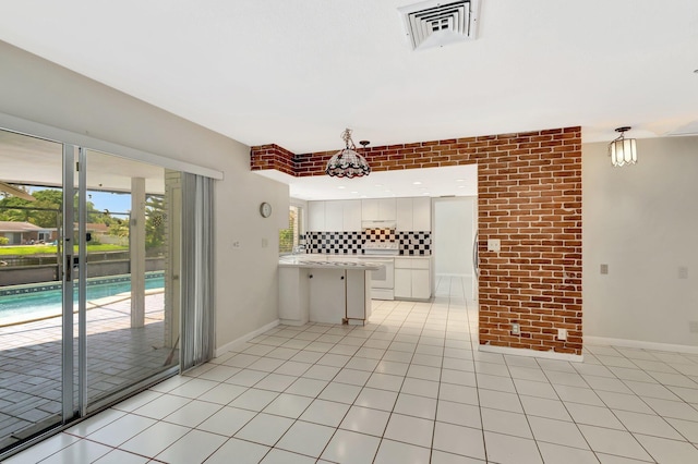 1746 W Terrace Dr, Lake Worth, FL 33460 - kitchen featuring electric range, light countertops, a peninsula, white cabinets, and backsplash