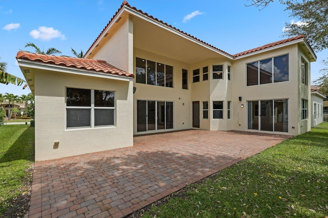 9682 Campi Dr, Lake Worth, FL 33467 - back of house with a patio area, stucco siding, a tiled roof, and a lawn