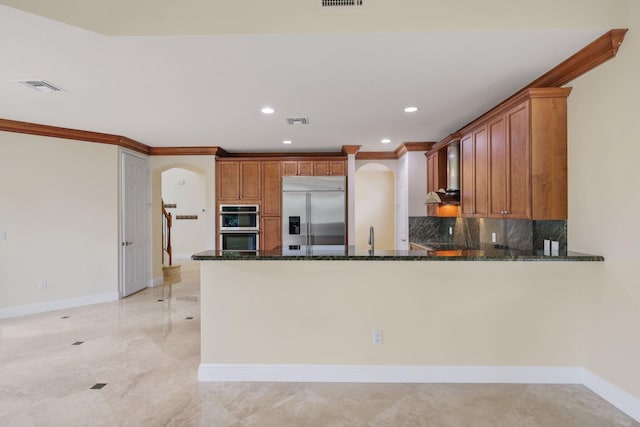 9682 Campi Dr, Lake Worth, FL 33467 - kitchen featuring arched walkways, wall chimney range hood, visible vents, dark stone countertops, and stainless steel appliances