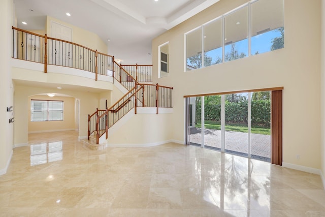 9682 Campi Dr, Lake Worth, FL 33467 - unfurnished living room with a wealth of natural light, arched walkways, baseboards, and stairs
