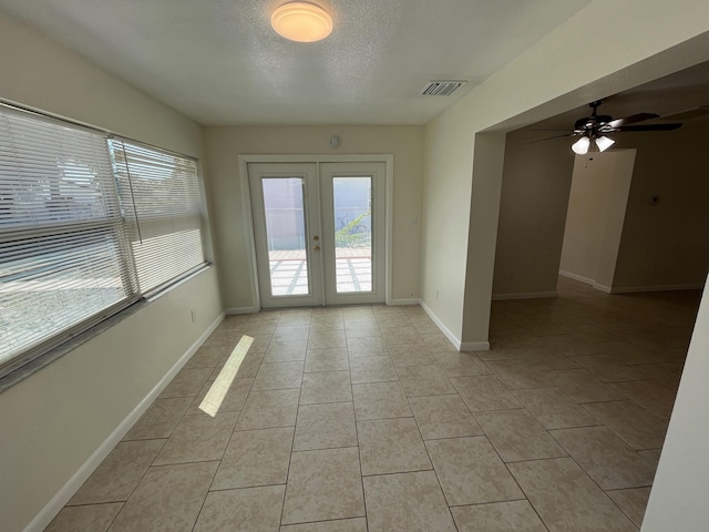 spare room featuring french doors, light tile patterned floors, a textured ceiling, visible vents, and a ceiling fan