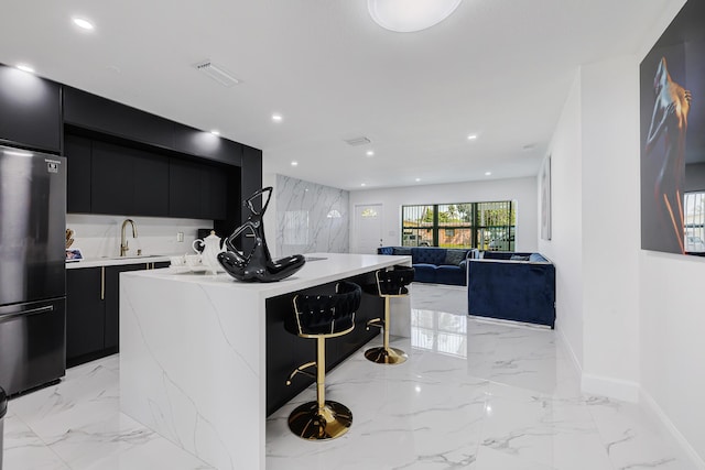 180 NW 18th St, Pompano Beach, FL 33060 - kitchen with a center island with sink, freestanding refrigerator, dark cabinetry, and modern cabinets