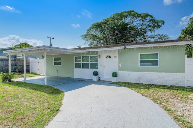 180 NW 18th St, Pompano Beach, FL 33060 - ranch-style home featuring fence, stucco siding, brick siding, an attached carport, and driveway