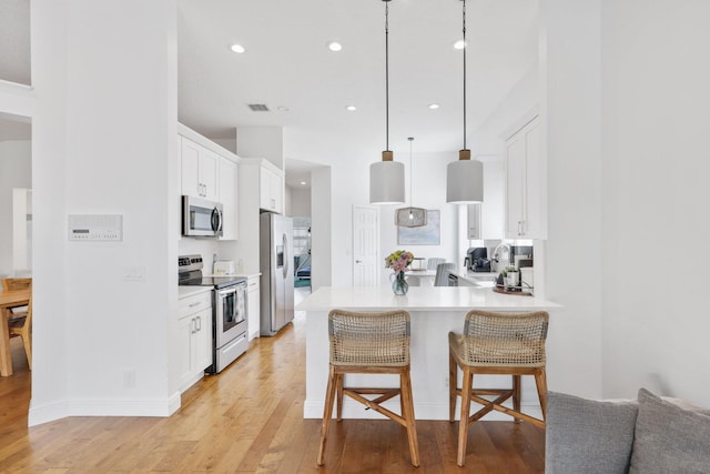 12761 Yardley Dr, Boca Raton, FL 33428 - kitchen with stainless steel appliances, light wood finished floors, a breakfast bar, and light countertops