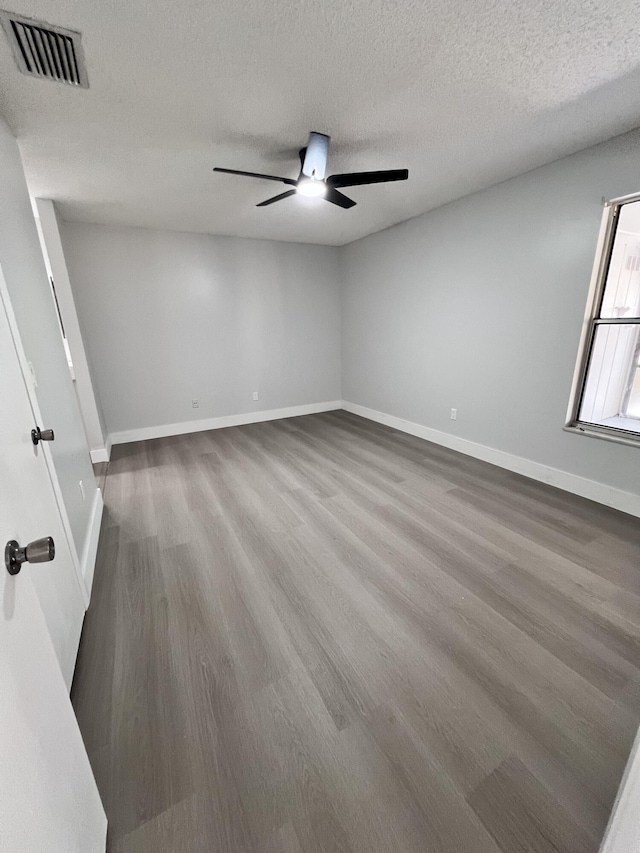 unfurnished room with baseboards, a textured ceiling, visible vents, a ceiling fan, and wood finished floors