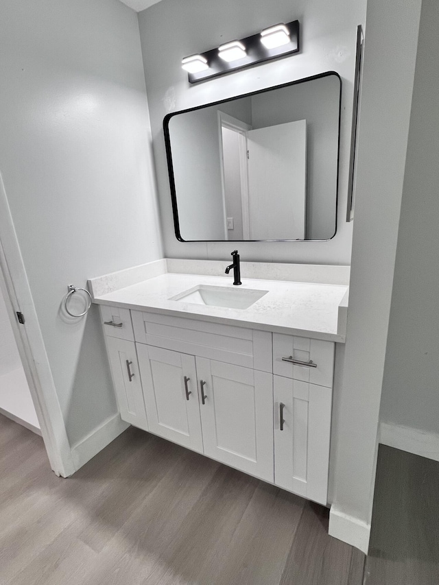 bathroom featuring baseboards, wood finished floors, and vanity