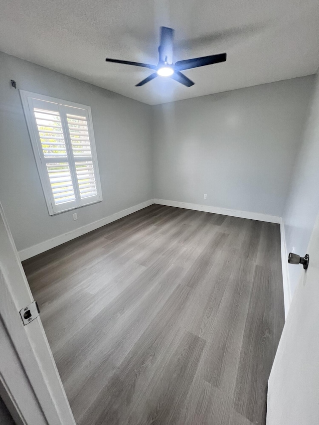 unfurnished room with baseboards, a textured ceiling, ceiling fan, and wood finished floors