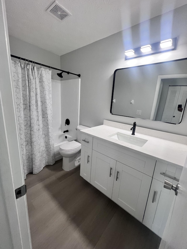 bathroom featuring a textured ceiling, wood finished floors, toilet, vanity, and shower / bathtub combination with curtain