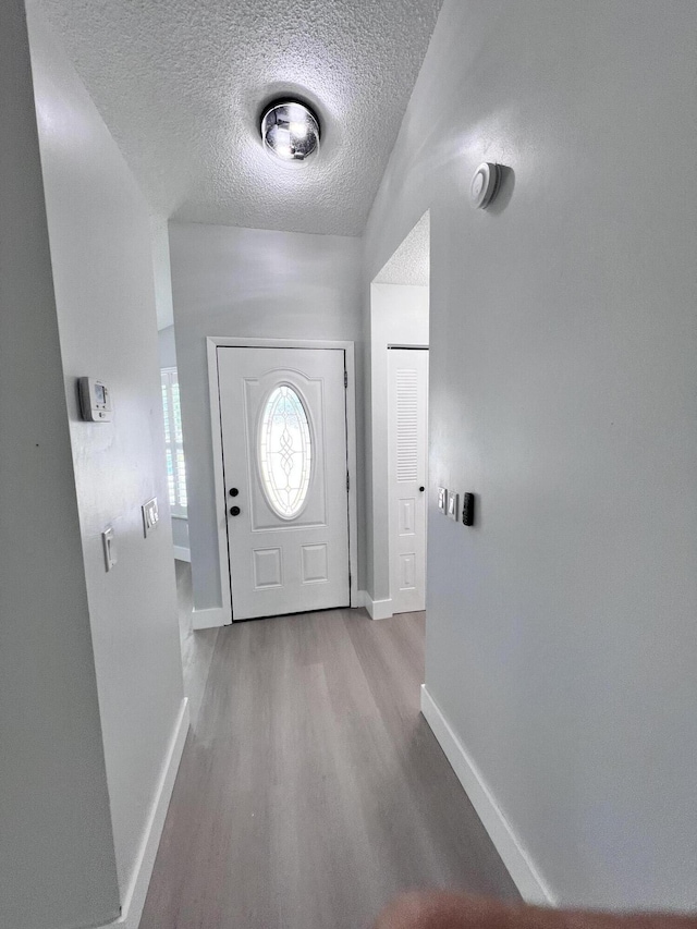 entrance foyer featuring baseboards, wood finished floors, and a textured ceiling