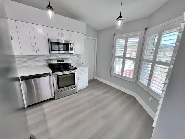 kitchen featuring backsplash, light countertops, appliances with stainless steel finishes, and white cabinets