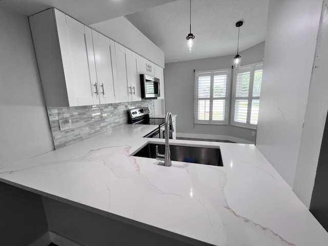 kitchen featuring a sink, pendant lighting, light stone countertops, appliances with stainless steel finishes, and decorative backsplash
