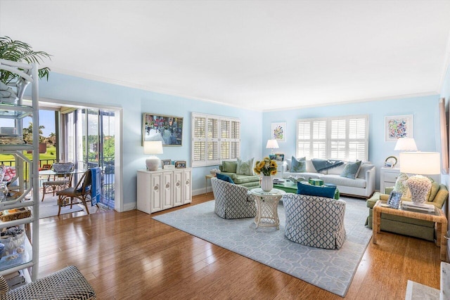 living room featuring baseboards, wood finished floors, and crown molding