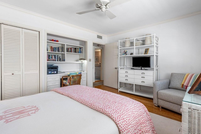 bedroom with a closet, visible vents, crown molding, wood finished floors, and a ceiling fan