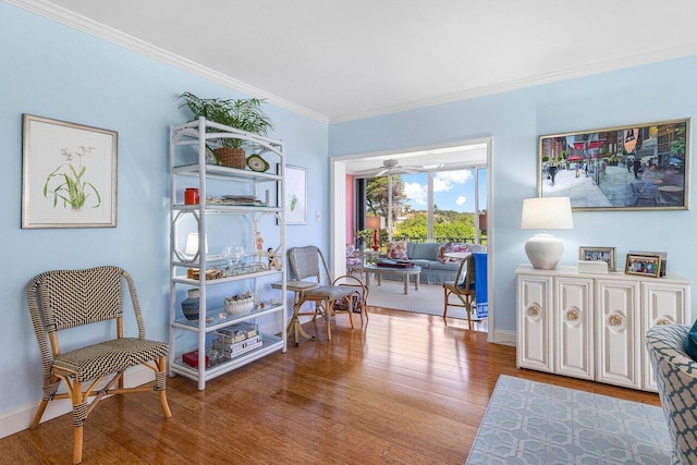 sitting room with baseboards, wood finished floors, and ornamental molding