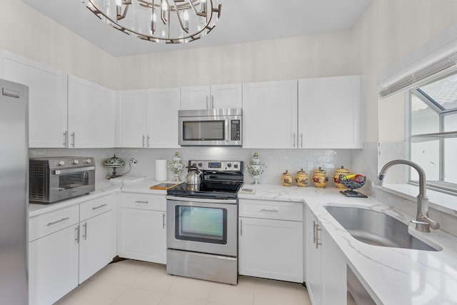 kitchen with a sink, light stone counters, white cabinets, a toaster, and stainless steel appliances