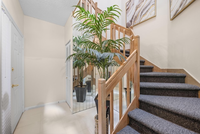 staircase with baseboards and a textured ceiling