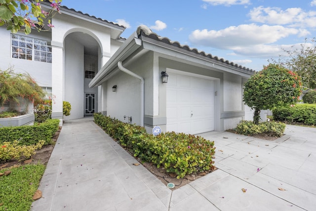 exterior space with a tiled roof, an attached garage, and stucco siding