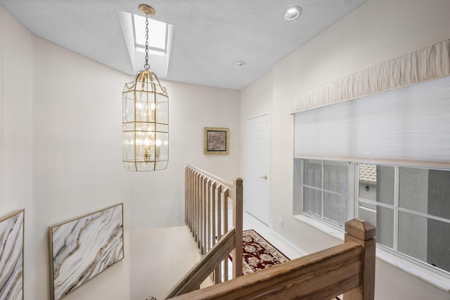 stairs featuring recessed lighting, a skylight, and a notable chandelier