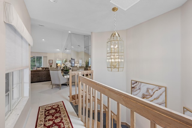 hall with an upstairs landing, light tile patterned flooring, a notable chandelier, and a skylight